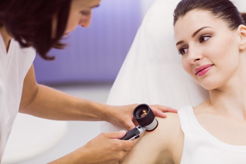 Dermatologist examining skin of patient with dermatoscope